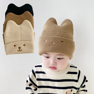 男の子にも女の子にもぴったりの、スタイリッシュでキュートなニットの冬用帽子。刺繍された顔、クマの耳、豆の形をした装飾が特徴です。